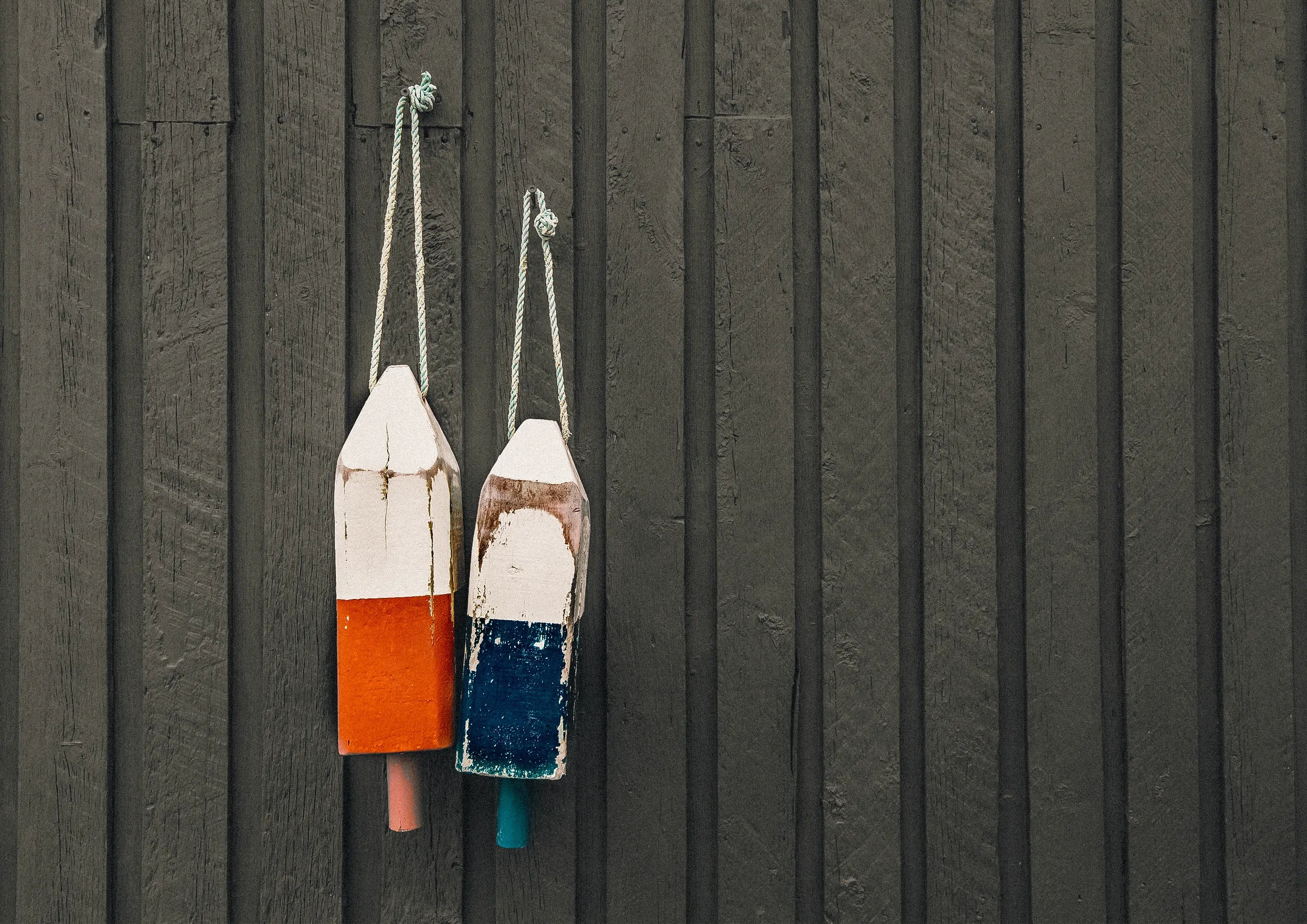 Two colorful buoys hanging against a dark wooden wall